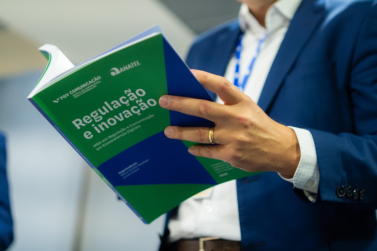 Participante segurando o livro Regulação e Inovação, publicação da FGV Comunicação com a ANATEL